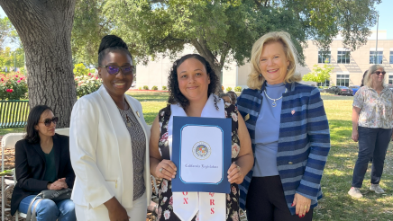 Assemblymember Rhodesia Ransom, and Stanislaus State President, Britt Rios-Ellis, with graduating student