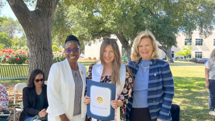 Assemblymember Rhodesia Ransom, and Stanislaus State President, Britt Rios-Ellis, with graduating student